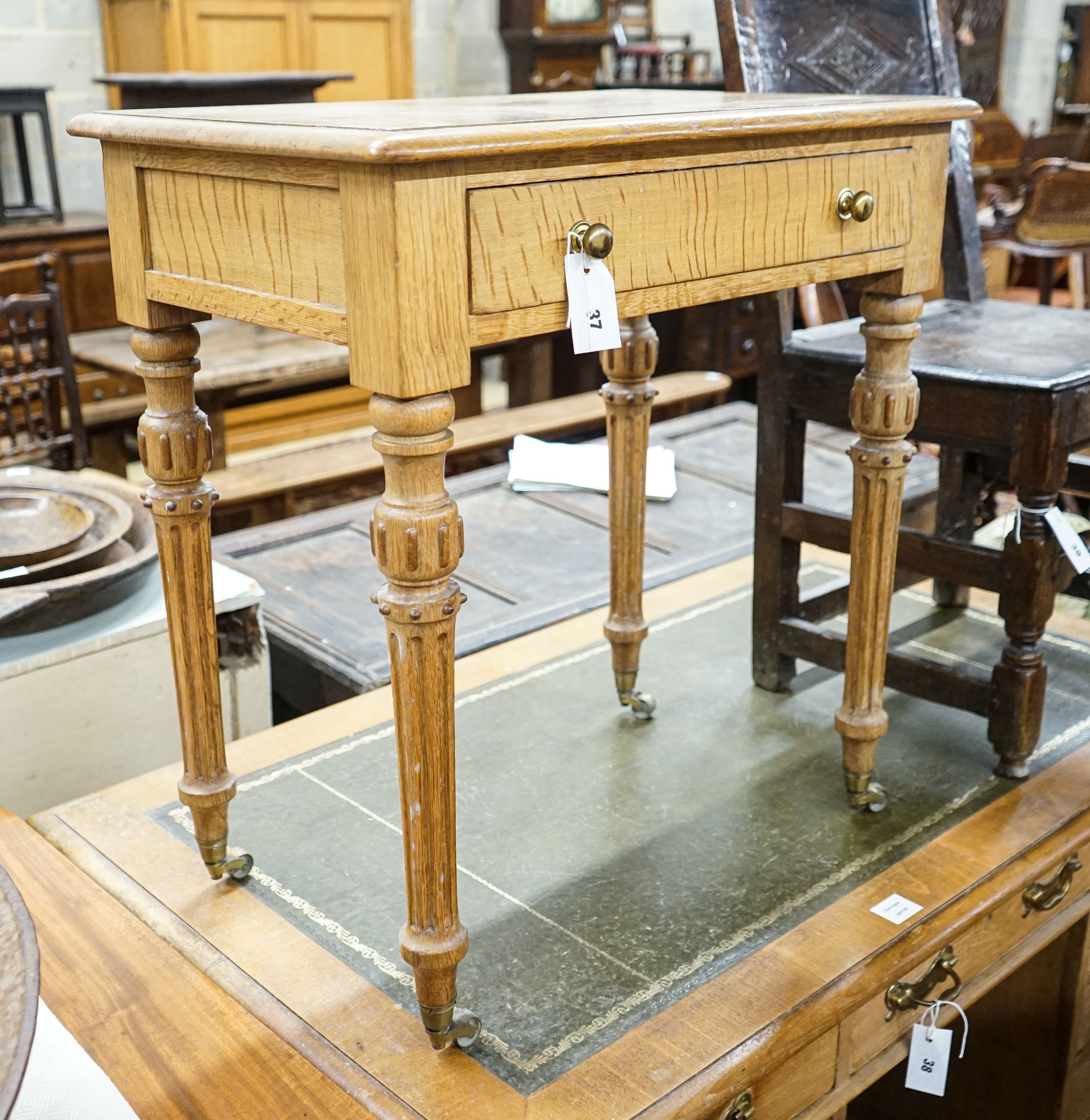 A Victorian golden oak side table, with single drawer, turned and fluted legs on brass castors, width 68cm, depth 46cm, height 73cm